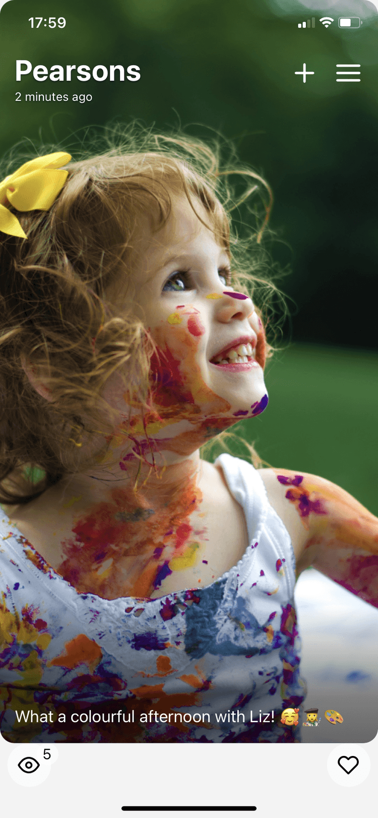 Mobile phone screen showing a photo of a smiling 5 year old girl with colorful paint all over her face.